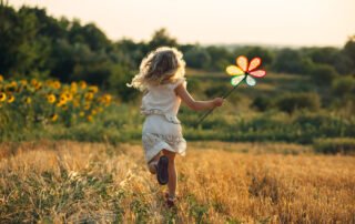 Cute little girl playing in the summer field of wheat